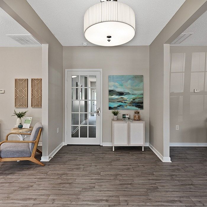 Inviting hallway featuring elegant hardwood floors, modern decor, and a chic glass door leading to spacious living areas.