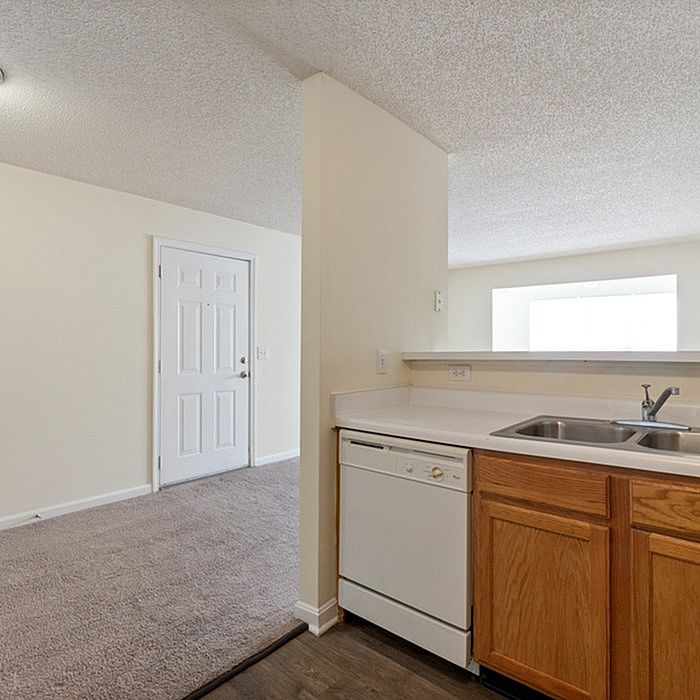 Inviting open space featuring a cozy kitchen with wood accents and adjacent carpeted area, ideal for comfortable living.