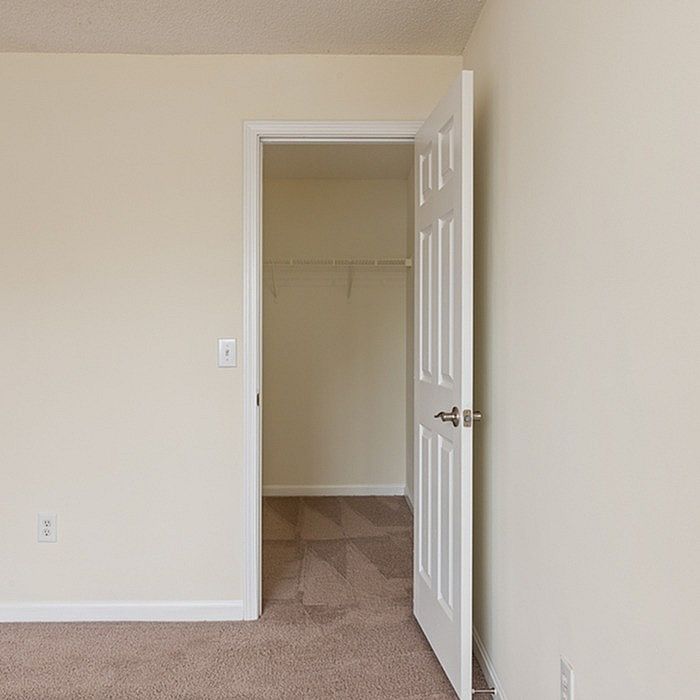 Spacious walk-in closet entry in a modern apartment with plush carpet flooring and neutral walls.