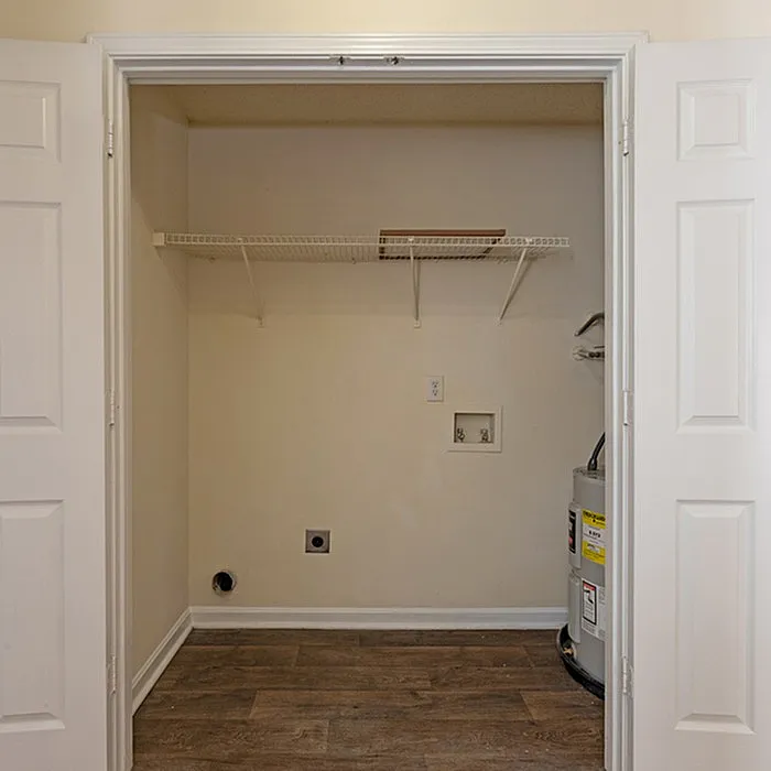 Efficient laundry area with utility hookups and sleek wood flooring, perfect for modern living.