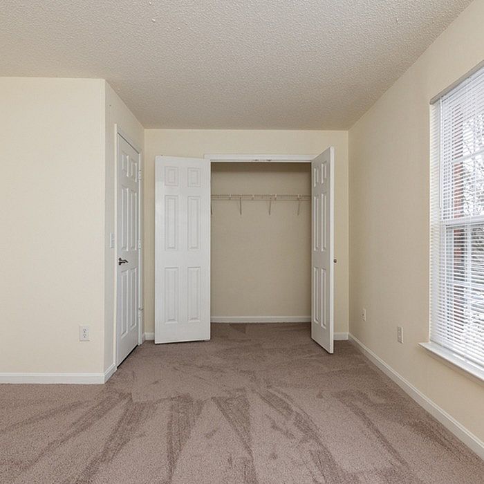 Bright and spacious bedroom with plush carpet, ample closet space, and a large window for natural light.