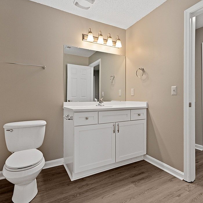 Modern bathroom with sleek white vanity, elegant lighting fixtures, and warm neutral tones. Perfect space for relaxation and refreshment.