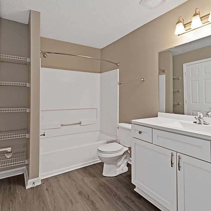 Elegant bathroom with modern fixtures, featuring a sleek vanity, spacious bathtub, and stylish wood-tone flooring.