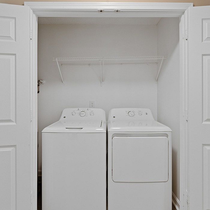 Compact laundry area with modern washer and dryer, enhanced by sleek white tones and handy storage shelving.