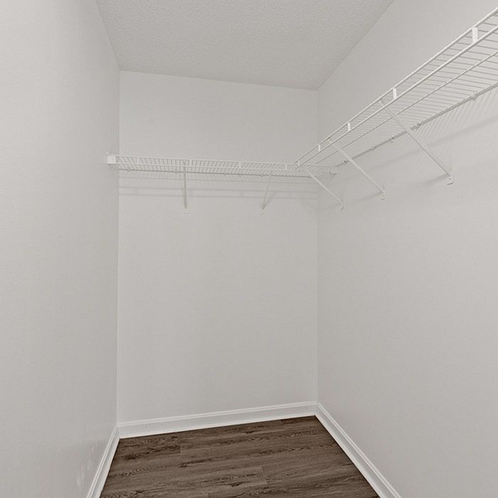 Spacious walk-in closet with sleek white walls and modern wire shelving, perfect for organized storage.
