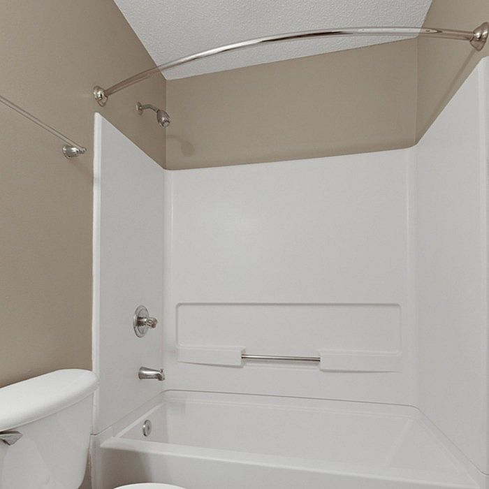 Elegant bathroom featuring a modern bathtub with a curved shower rod, sleek fixtures, and neutral color palette.