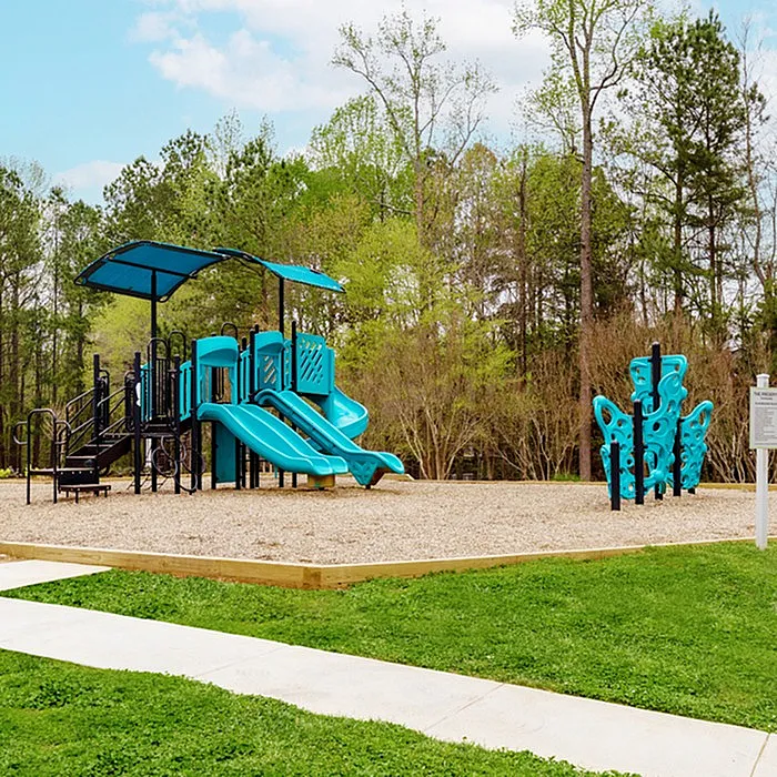 Inviting playground with vibrant blue slides and climbing structure surrounded by lush greenery, perfect for family enjoyment.