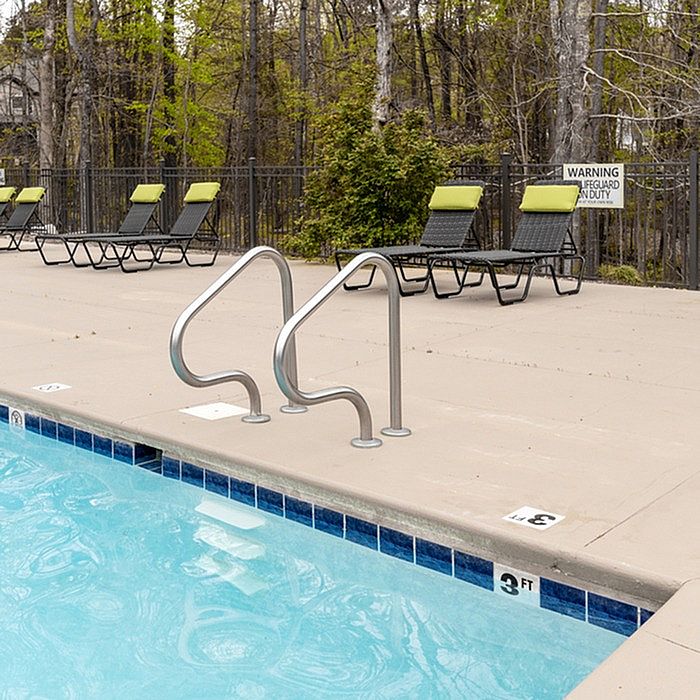Inviting outdoor pool area with bright sun loungers, nestled in a serene wooded setting.