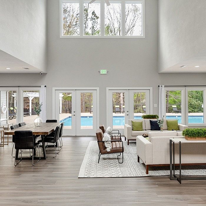 Spacious and elegant living area with high ceilings, modern decor, and a view of the inviting swimming pool through large windows.