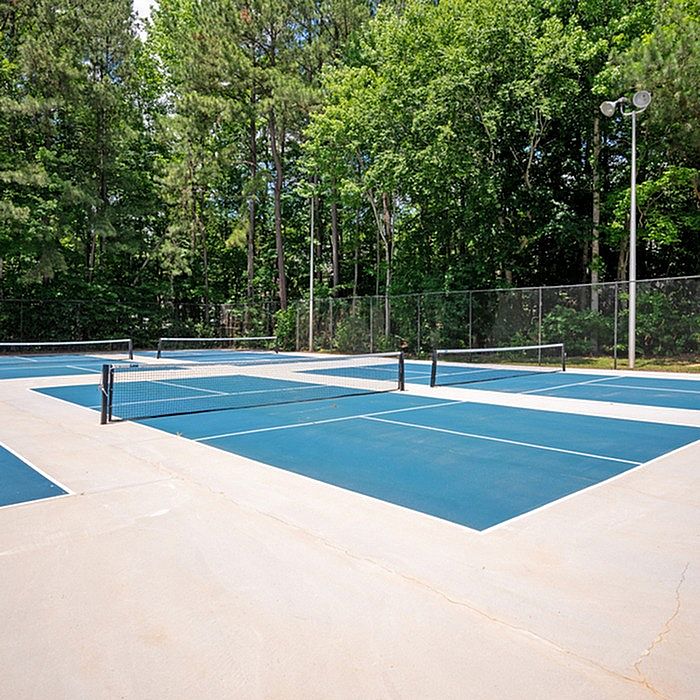 Vibrant outdoor tennis courts surrounded by lush green trees, perfect for sports enthusiasts.