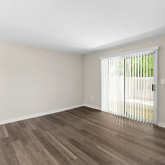 Bright, spacious living area with sleek hardwood flooring and large sliding glass doors opening to private outdoor space.