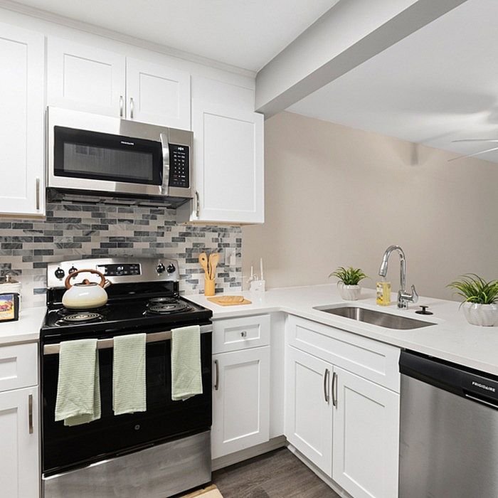 Modern kitchen with sleek white cabinetry, stainless steel appliances, and a stylish tile backsplash, offering a bright and welcoming cooking space.