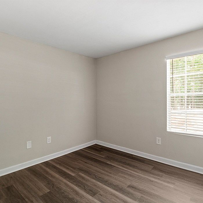 Bright and inviting empty room with elegant wood flooring and ample natural light flowing through the window.
