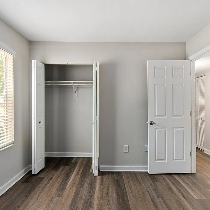 Bright and spacious bedroom with elegant hardwood floors and ample closet space in a modern apartment.