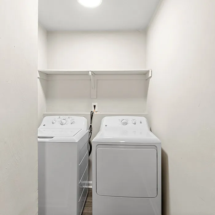 Bright laundry room featuring a modern washer and dryer set with an overhead storage shelf, offering convenience and style.
