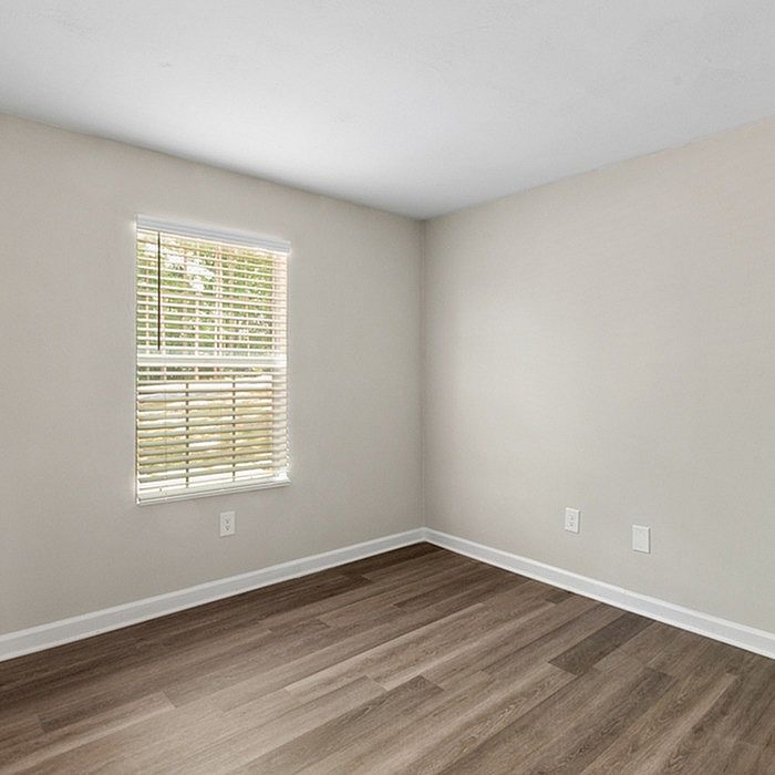 Bright and inviting empty room with large window and elegant hardwood flooring.
