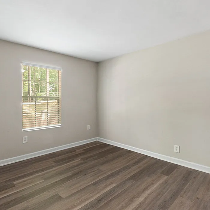 Bright, airy room with sleek wood flooring and a large window allowing natural light to flood in.