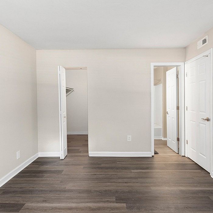 Bright and inviting bedroom with sleek wood flooring, spacious walk-in closet, and modern bathroom access.
