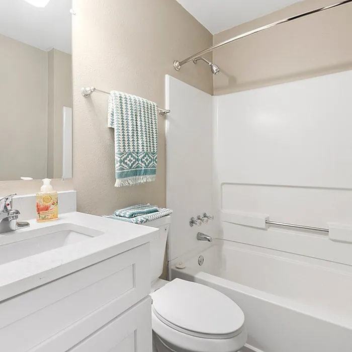 Bright and modern bathroom featuring a sleek white vanity, stylish fixtures, and a cozy bathtub with chic decor.