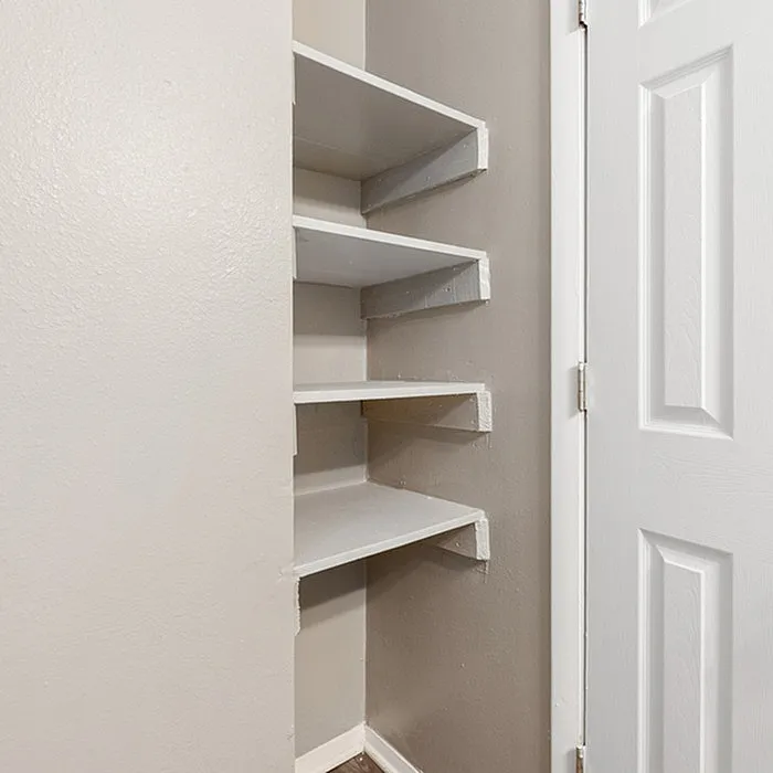 Compact corner shelving unit with sleek white shelves, perfect for maximizing storage and adding modern elegance to any room.