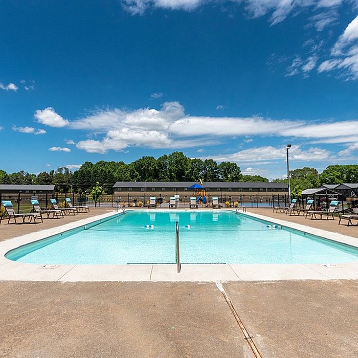 Inviting outdoor swimming pool with lounge chairs and a clear blue sky, perfect for relaxation and enjoyment.