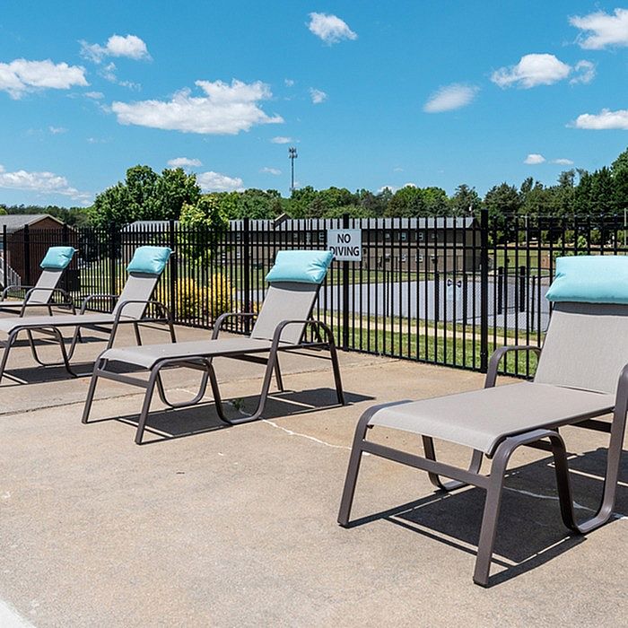 Inviting poolside area with comfortable lounge chairs and scenic views, perfect for relaxing under the sunny blue sky.