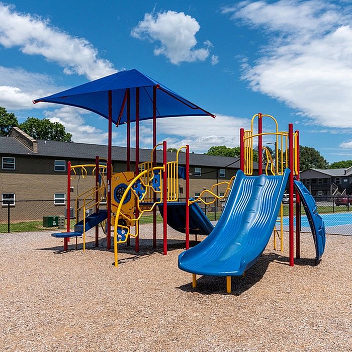 Vibrant playground with colorful slides and climbing structures set under a bright blue sky, ideal for family fun in a welcoming community.