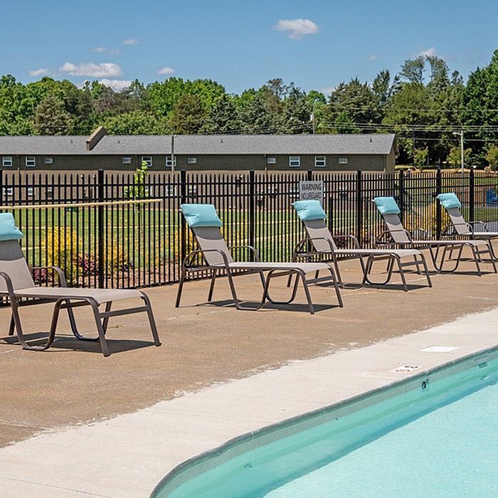 Inviting outdoor pool area with comfortable lounge chairs under a bright blue sky, ideal for relaxation and leisure.