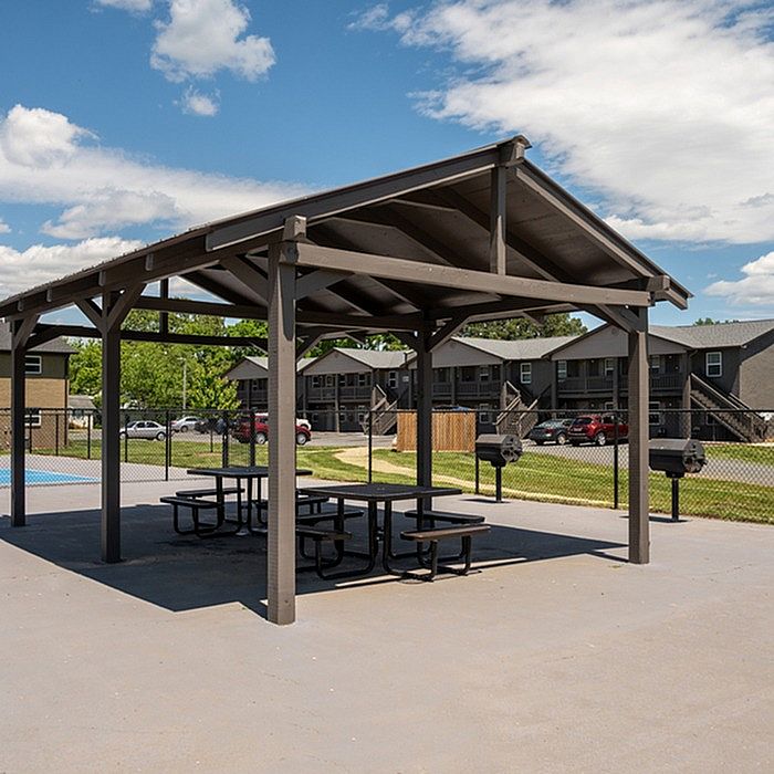 Charming outdoor pavilion with picnic tables, perfect for gatherings in a serene apartment complex.
