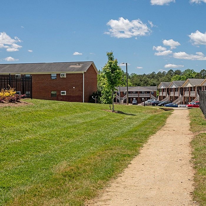 Inviting apartment complex with well-maintained green spaces and serene walking paths under a clear blue sky.