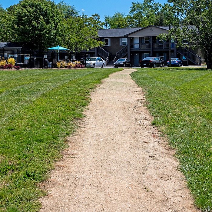 Charming apartment complex with cozy front yard path, lush greenery, and convenient parking.