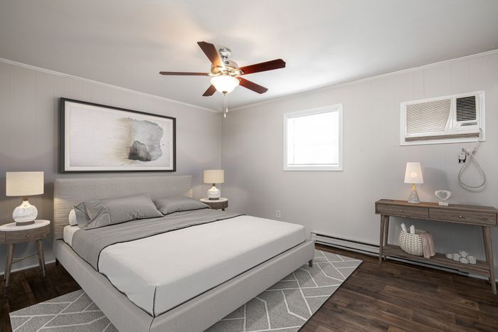 Inviting bedroom with modern decor, featuring a chic grey bed, elegant side tables with lamps, and a stylish ceiling fan.