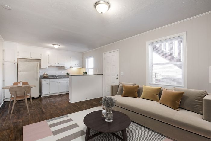 Inviting open-concept living space showcasing a modern kitchen with white cabinetry, cozy dining area, and a stylish living room with plush seating.
