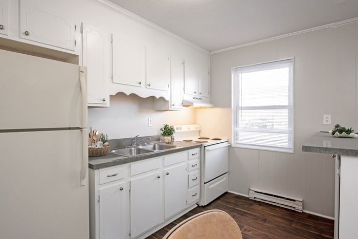 Bright and inviting kitchen with classic white cabinetry, stainless steel sink, and sunlit window.
