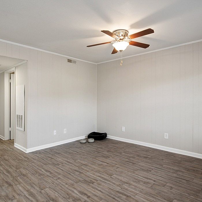 Bright and spacious room featuring elegant wood-look flooring and a modern ceiling fan, perfect for a cozy living area.