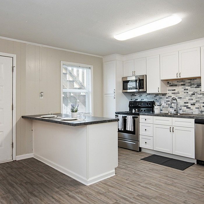 Modern kitchen featuring sleek white cabinetry, stainless steel appliances, and a stylish grey-tile backsplash.