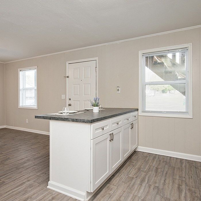Inviting kitchen area with a sleek, modern island, natural light pouring through large windows, and elegant wood flooring.