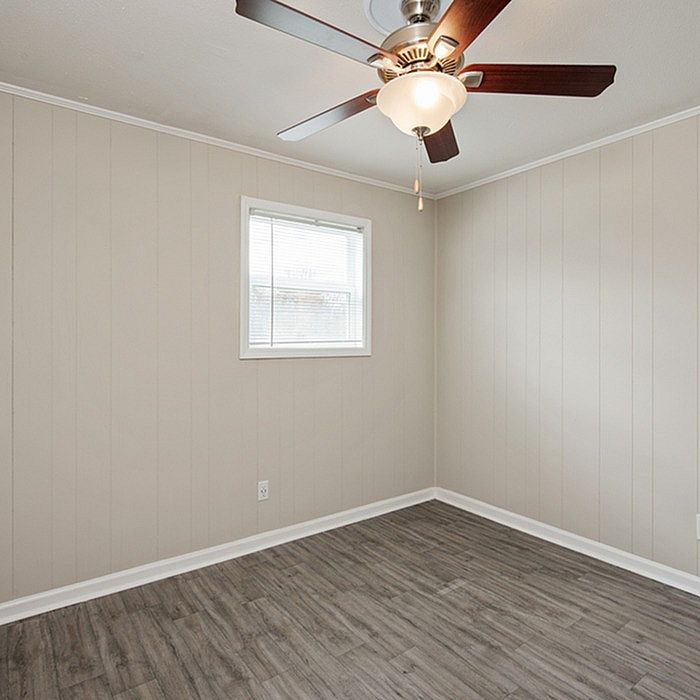 Bright room with sleek laminate flooring, neutral walls, and a modern ceiling fan, perfect for versatile styling.