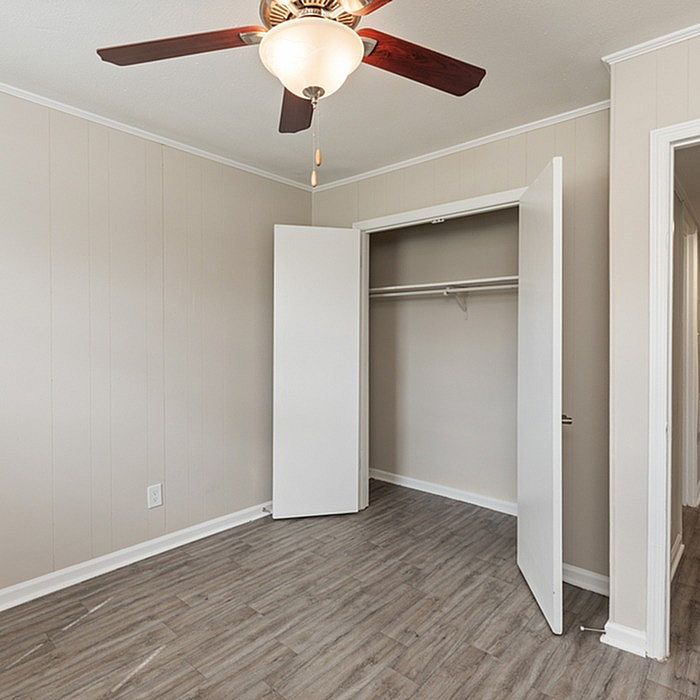 Inviting bedroom with modern gray flooring, spacious closet, and elegant ceiling fan, perfect for a cozy retreat.
