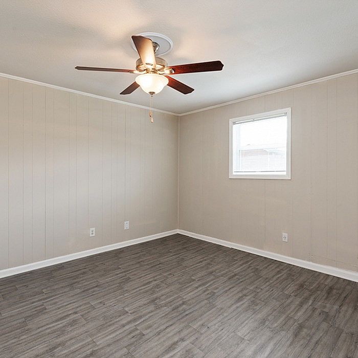 Bright and airy room featuring elegant wood flooring and a modern ceiling fan, perfect for a cozy living space.