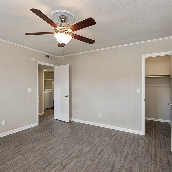 Bright and airy bedroom with modern ceiling fan and elegant wood flooring, leading to a spacious closet and adjacent utility area.