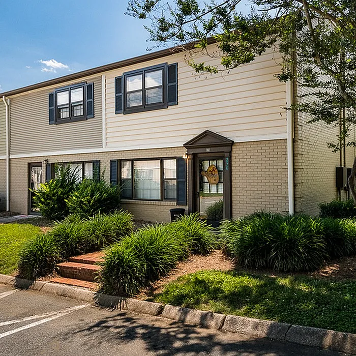Charming two-story brick townhouse with manicured greenery and ample natural light.