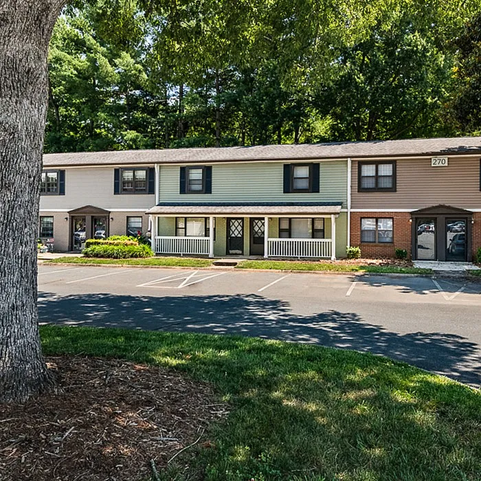 Charming townhouse with a classic facade nestled in a lush green setting, offering a peaceful and friendly neighborhood vibe.
