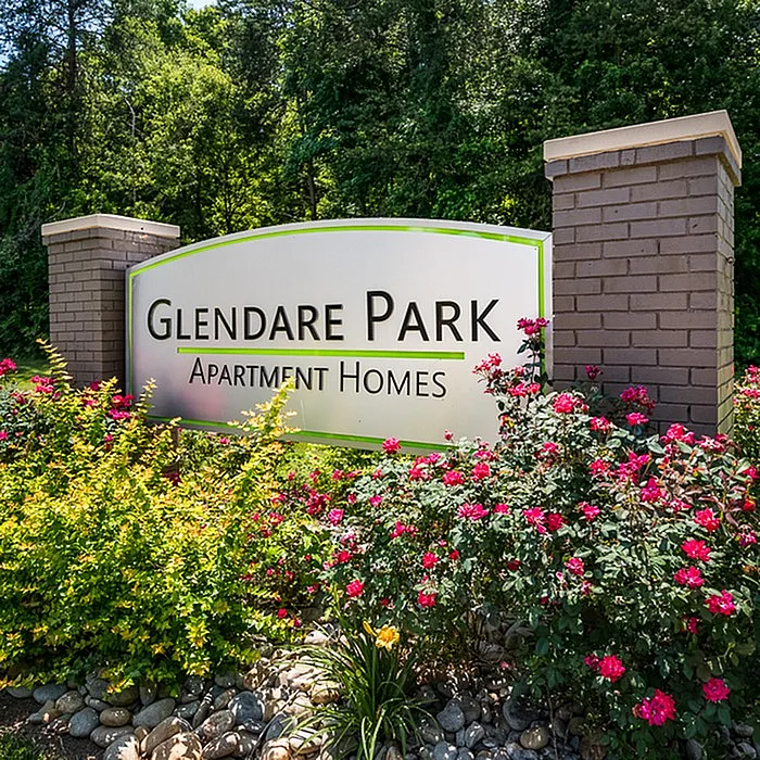 Welcoming entrance sign of Glendare Park Apartment Homes, surrounded by vibrant flowers and lush greenery.
