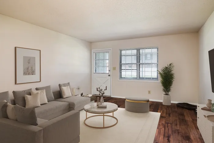 Elegant living room with stylish gray sectional sofa, chic round coffee table, and bright natural light through large windows, perfect for relaxation and entertainment.