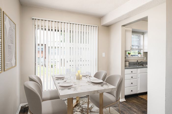 Bright dining area featuring a chic marble table and elegant chairs with a view into a compact, contemporary kitchen.