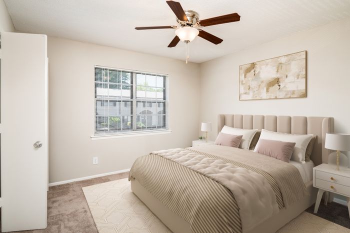 Elegant bedroom featuring a cushioned headboard bed, large window with garden view, and modern ceiling fan.