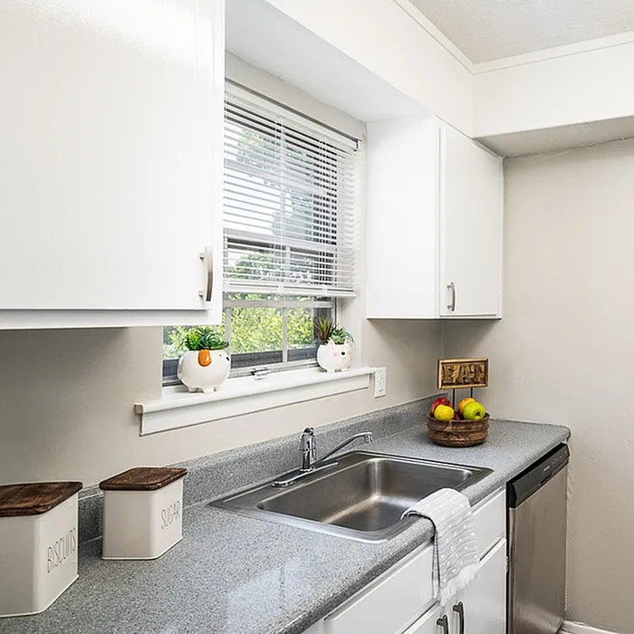 Charming kitchen with sleek granite countertops, bright white cabinets, and sunlit window view, perfect for a cozy dining experience.