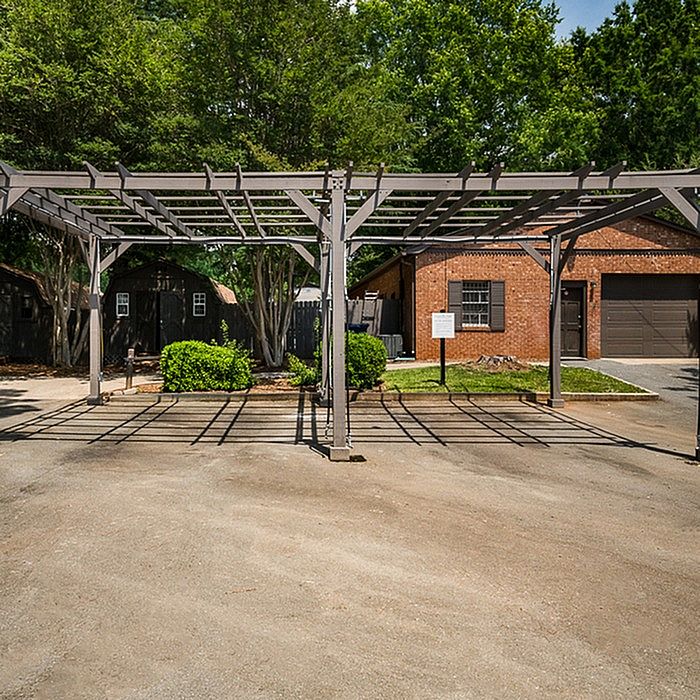 Charming outdoor view featuring a stylish pergola, lush greenery, and a rustic brick garage in a serene setting.
