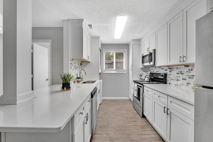 Chic modern kitchen with sleek white cabinets, stainless steel appliances, and stylish tile backsplash, perfect for culinary enthusiasts.
